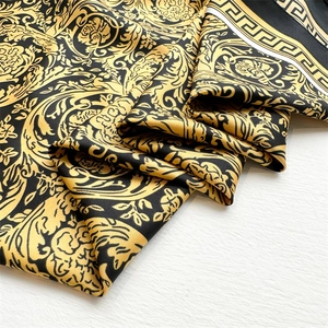 Close-up of golden Baroque floral patterns and Greek Key border on silk scarf fabric
