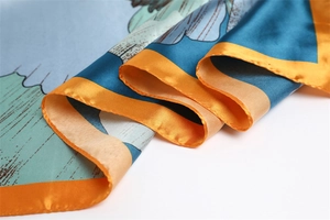 Detailed macro view of vibrant blue and orange gradient floral satin silk scarf texture