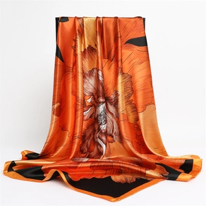 Close-up of bright orange floral silk scarf with glossy satin finish and elegant drape