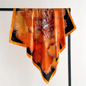 Close-up of orange and black floral satin scarf with high-gloss finish and rolled edges
