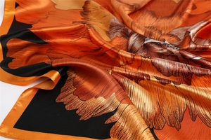 Detailed close-up of glossy floral satin scarf with vibrant orange petals and black borders