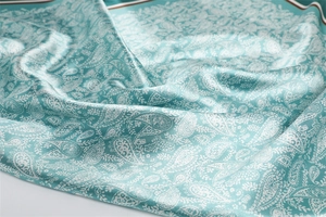 Detailed view of teal paisley silk scarf featuring fine patterns and border stripes