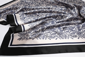 Close-up of luxury paisley print silk scarf with black and white striped border details