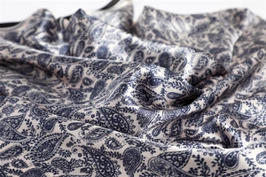 Detailed macro view of the smooth blue paisley satin fabric with elegant drape and luster