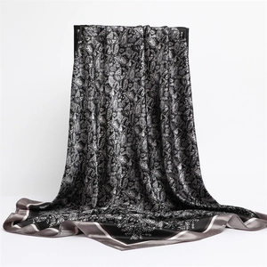 Detailed view of paisley silk scarf with glossy texture and striped border contrast