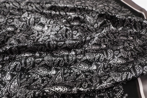 Detailed view of the smooth black and white paisley pattern satin silk scarf fabric