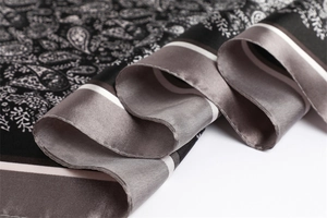 Detailed close-up of paisley pattern silk scarf with elegant black and white borders