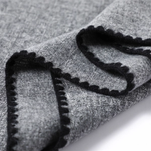 Detail of grey cashmere scarf with black scalloped edge and soft knit texture