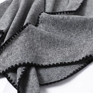 Close-up of grey cashmere-feel shawl fabric featuring black scalloped edge stitching