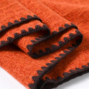 Close-up of orange cashmere-like scarf with brown wavy crochet trim and thick texture