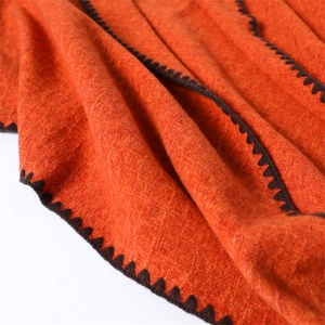 Detail of orange cashmere-like scarf showing diamond knit texture and dark stitched edges