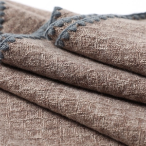 Close-up of thick tan cashmere-feel fabric with dark grey crochet lace edge trim