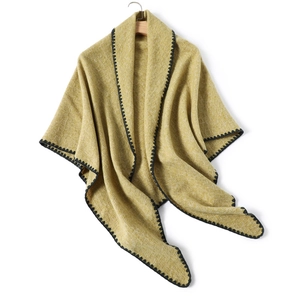 Ginger yellow knitted shawl with black wavy embroidery hanging on a wooden hanger