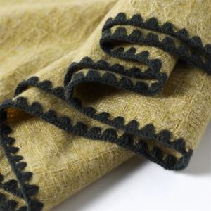 Detailed close-up of ginger yellow knit scarf with decorative black lace crochet border