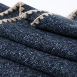 Macro detail of dark blue scarf fabric with premium beige zigzag embroidery stitching
