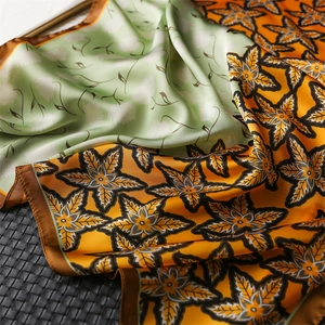 Close-up of double-sided silk scarf featuring orange maple leaves and mint green floral print