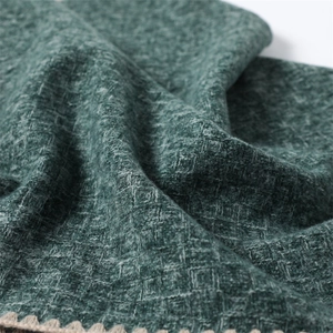 Close-up of dark green cashmere-like scarf with knitted waffle texture and beige crochet edge