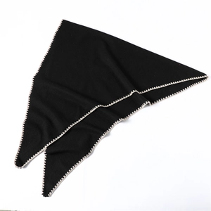 Detail of black cashmere-like triangle scarf featuring cream wavy crochet edge texture