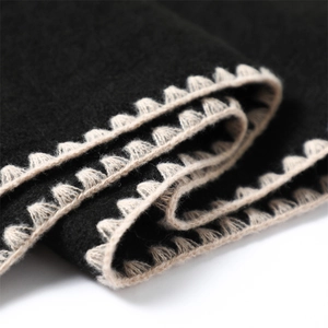 Detailed close-up of cashmere-like fabric with elegant scalloped crochet stitching edges