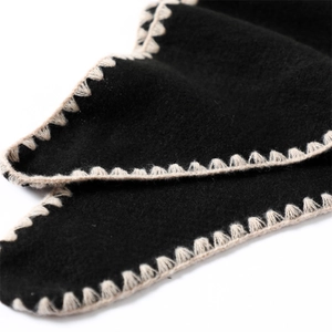 Macro detail of black cashmere shawl with contrast white whipstitch embroidery edges