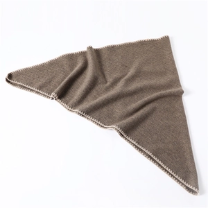 Detail of dark brown cashmere-style scarf featuring light beige scalloped edge stitching