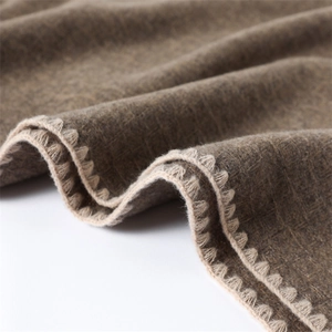 Macro view of earth-tone cashmere-like scarf with white scalloped edge detailing