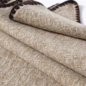 Detailed macro view of soft camel knit shawl featuring textured diamond weave and dark edges