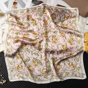 Détail d'un foulard en soie rose avec motifs de roses jaunes et volutes classiques