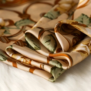 Détail macro d'un foulard en satin de soie avec motifs floraux vintage sur fond doré