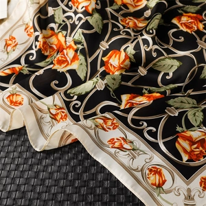 Gros plan d'un foulard en soie noir avec des roses orange et des motifs vintage
