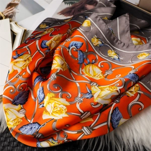 Détail d'un élégant foulard en soie orange avec imprimé de roses jaunes et volutes