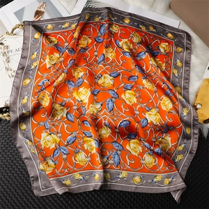 Détail de la texture satinée du foulard carré orange avec des motifs de roses élégantes