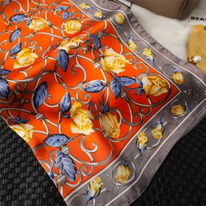 Détails d'un foulard en soie orange avec motif de roses jaunes et treillis élégants