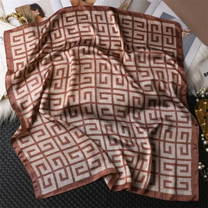 Gros plan d'un foulard carré en soie avec motifs géométriques marron et drapé élégant