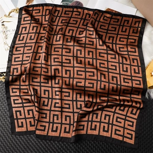 Détail d'un foulard carré en soie avec des motifs géométriques marron et une bordure