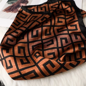 Vue détaillée d'un foulard en soie de luxe avec motifs géométriques sur fond marron-orange