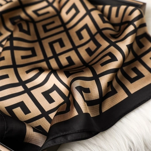 Détail du motif géométrique noir et champagne sur un foulard carré en soie artificielle