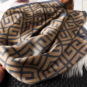 Gros plan sur la texture jacquard géométrique du foulard en soie au fini brillant