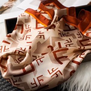 Détail d'un élégant foulard en soie aux motifs géométriques orange et bord en satin