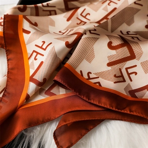 Détail d'un élégant foulard en soie avec des motifs géométriques orange et beige