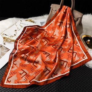 Élégant foulard carré en soie orange à imprimé géométrique drapé sur un sac à main