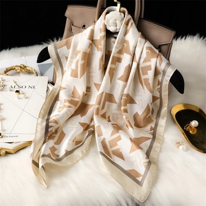 Élégant foulard en soie beige à motifs géométriques marron sur un sac en cuir marron