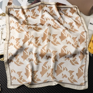 Détail de l'imprimé géométrique sur foulard en soie beige avec accessoires de mode