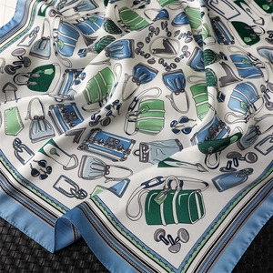 Detail showing smooth silk-like fabric texture with elegant handbag prints on light blue scarf