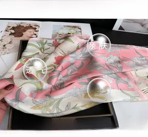 Close-up of pink iris floral silk scarf with elegant pattern on a black decorative tray