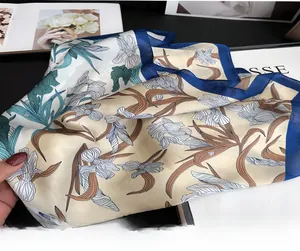 Close-up of elegant iris floral print silk scarf with navy blue hem on art background