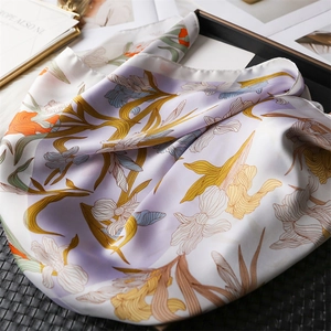 Detail of iris floral silk scarf with vibrant orange flowers on light purple background