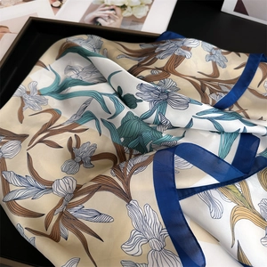 Detailed close-up of silk-textured iris print scarf with navy blue hem on elegant backdrop