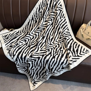 Classic zebra pattern square silk scarf displayed elegantly on a leather sofa with a beige bag