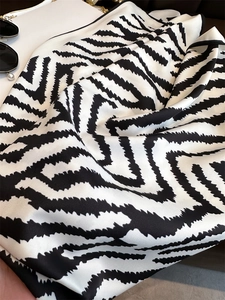 Close-up of zebra pattern silk scarf with black rolled hem and elegant smooth texture